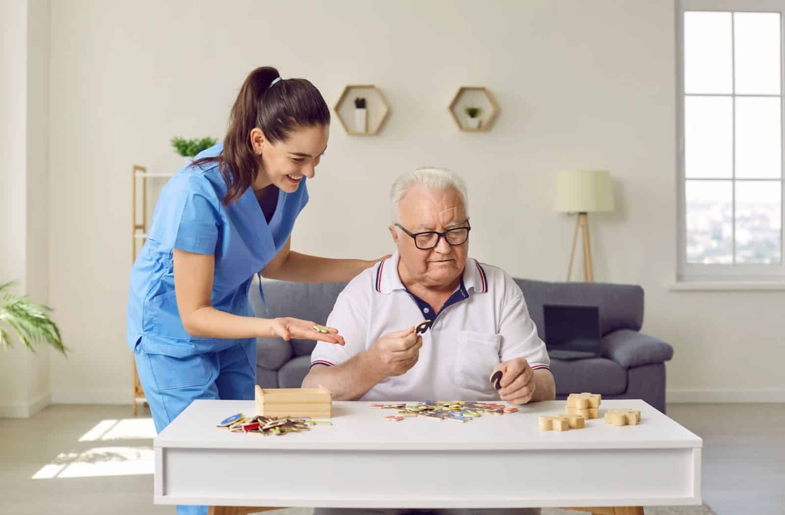 an older person is doing a puzzle that supports memory in their memory care facilitiy with their health care aid.